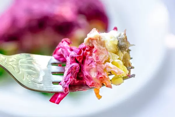 Close - up of a fork with vegetable salad with mayonnaise