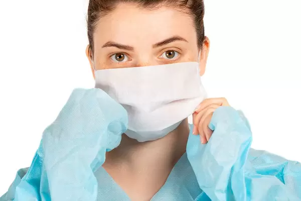 Close-up of a girl in a medical mask and dressing gown