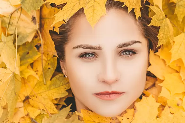 Close-up of a girl's face surrounded by yellow maple leaves