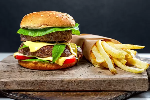 Close-up of a hamburger with French fries on old kitchen boards with black background behind (Flip 2019)