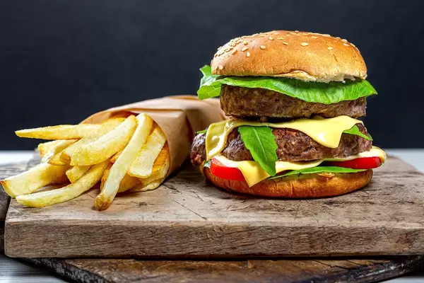 Close-up of a hamburger with French fries on old kitchen boards with black background behind
