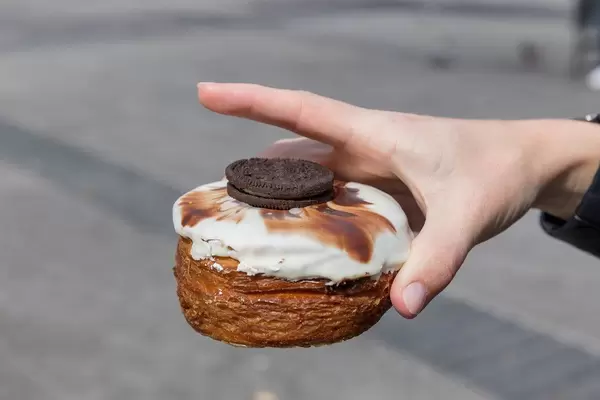 Close-Up of a hand holding a puff pastry Kronut with white chocolate icing made by  delicatessen shop "chök" in Barcelona, Spain