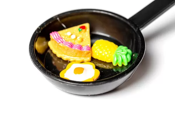 Close-up of a magnet toy frying pan with an egg, a piece of cake and a pineapple (Flip 2020)