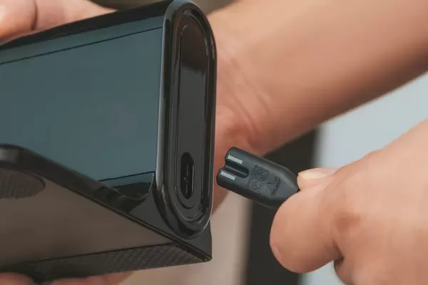 Close-up of a man connecting a cable to the charger of a robot vacuum cleaner