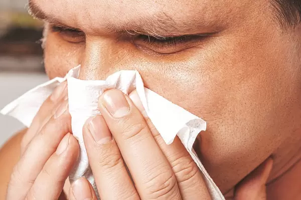 Close-up of a man with a runny nose holding a napkin near his nose (Flip 2019)