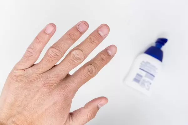 Close-up of a man's hand with liquid soap in the background