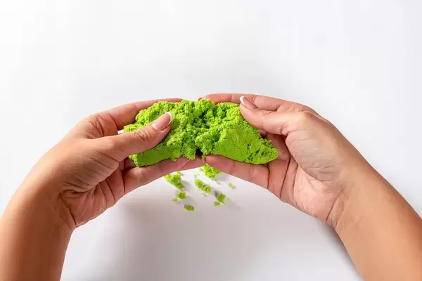 Close-up of a photo in the hands of kinetic sand on a white background