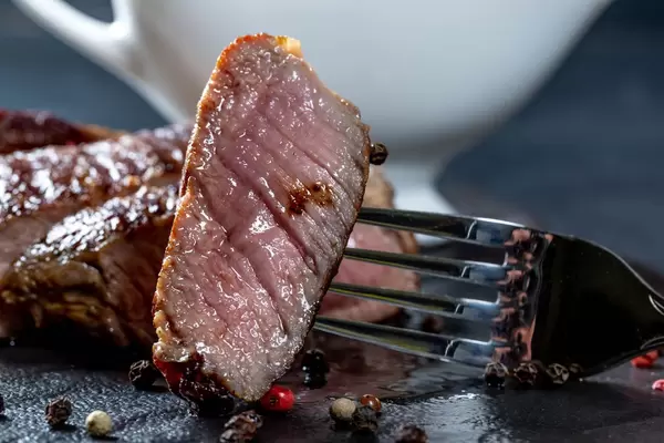 Close-up of a piece of juicy steak on a fork