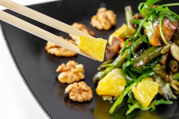 Close-up of a piece of orange in wooden chopsticks (Flip 2019)