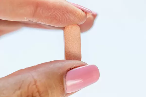 Close-up of a pink tablet in the hand of a girl with a pink manicure