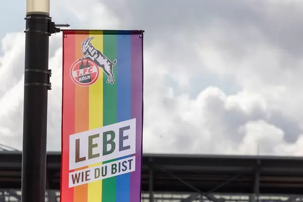 Close-up of a rainbow flag of German soccer team 1. FC Köln, with text "live as you are" (lebe wie du bist) for diversity day