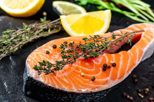 Close-up of a slice of salmon with fresh thyme and lemon slices
