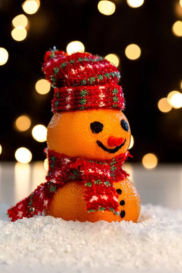 Close up of a snowman made of tangerines on the snow