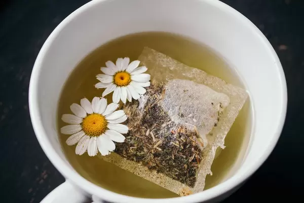 Close up of a tea with a teabag and camomile fower in a cup