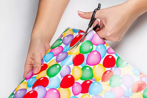 Close-up of a woman cutting gift wrapping paper with scissors (Flip 2019)