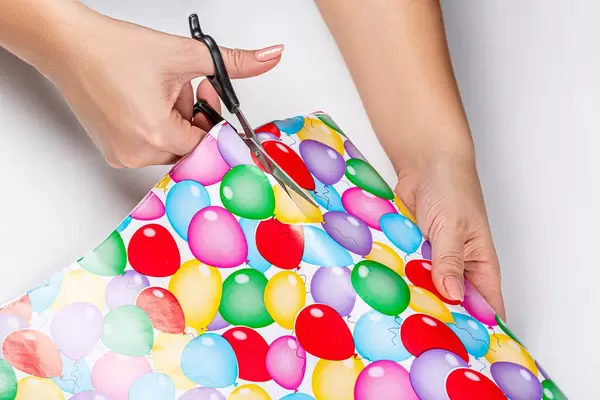 Close-up of a woman cutting gift wrapping paper with scissors