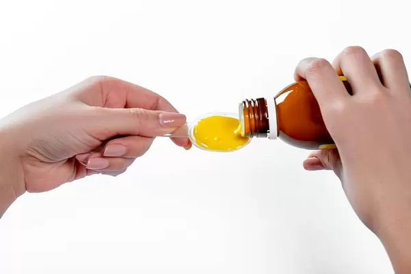 Close-up of a woman pours a spoon of medicinal mixture