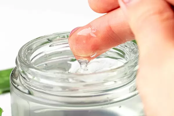 Close-up of a woman's hand and aloe Vera gel in a glass jar (Flip 2020)