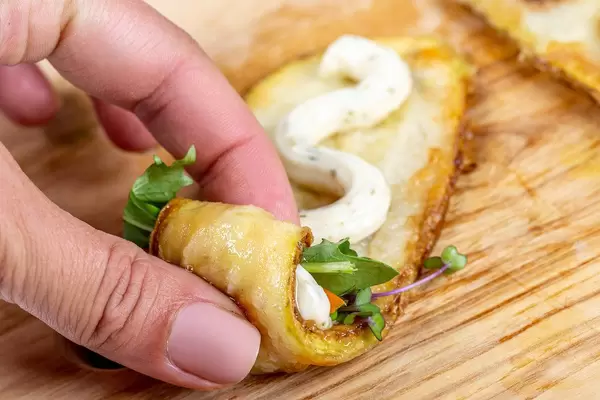 Close-up of a woman's hand rolling up zucchini rolls