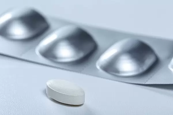 Close up of antibiotic tablet and blister behind her