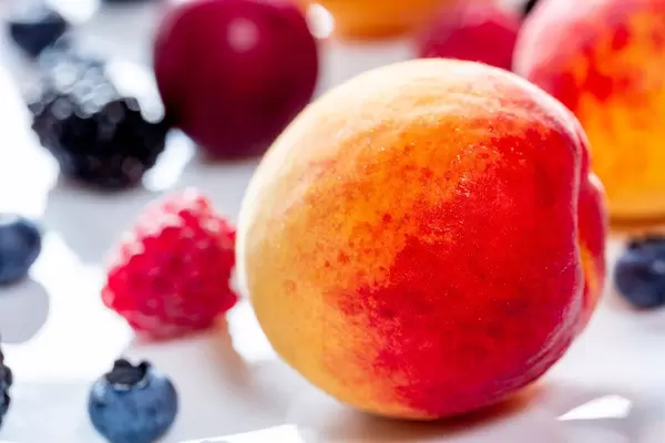 Close-up of apricot on the background of raspberries and blueberries