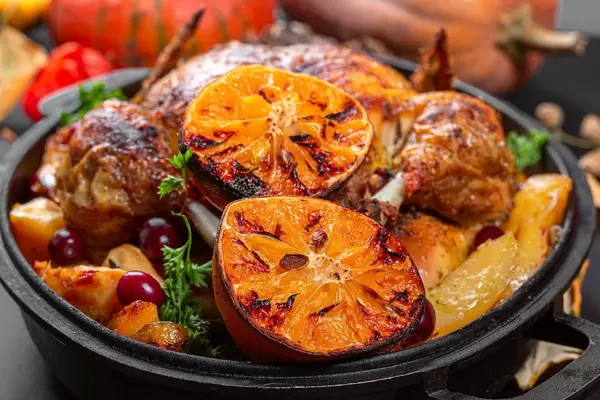 Close-up of baked chicken with oranges and potatoes on a baking sheet