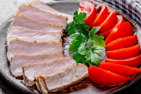 Close-up of baked meat with sliced tomatoes and parsley