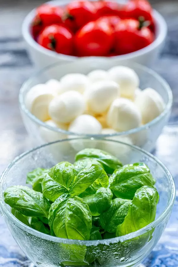 Close-up of Basil leaves and tomatoes with mozzarella behind (Flip 2019) (Flip 2019)