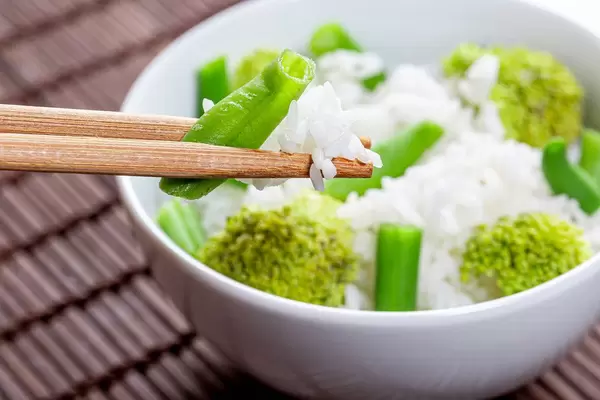Close up of boiled rice with asparagus and broccoli in a white bowl