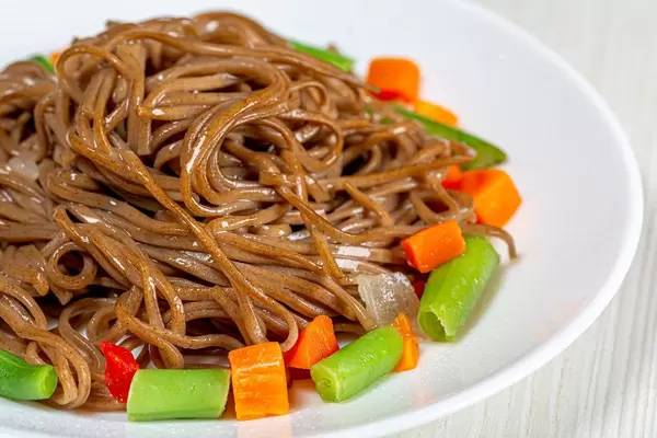 Close-up of buckwheat soba noodles with asparagus, carrots and sweet peppers