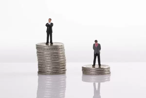 Close up of businessman miniature people figures standing with stack of coins
