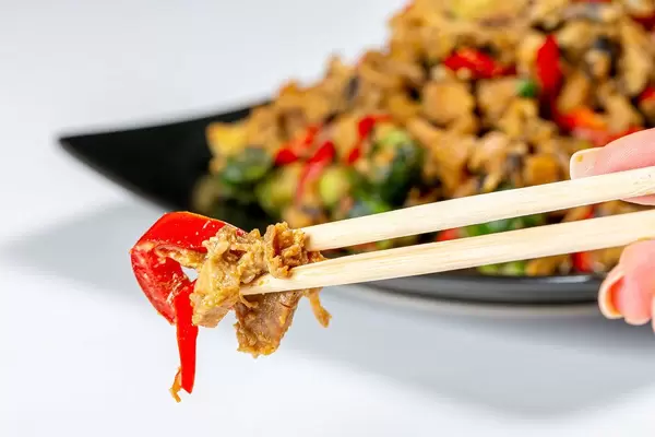 Close-up of chicken with vegetables in spicy sauce and chopsticks. The concept of Chinese food (Flip 2019)