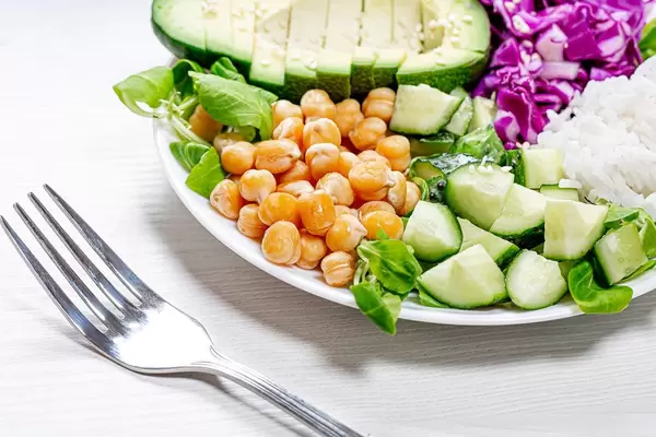 Close up of chickpeas with sliced vegetables and rice on a plate