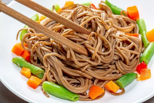 Close up of chopsticks and soba with vegetables