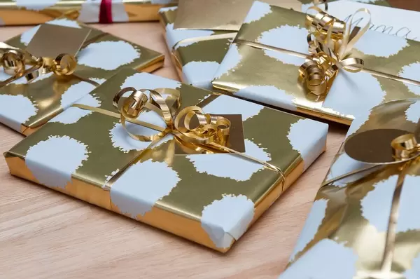 Close Up of Christmas Presents in Golden Gift Wrapping in different Sizes on Wooden Table