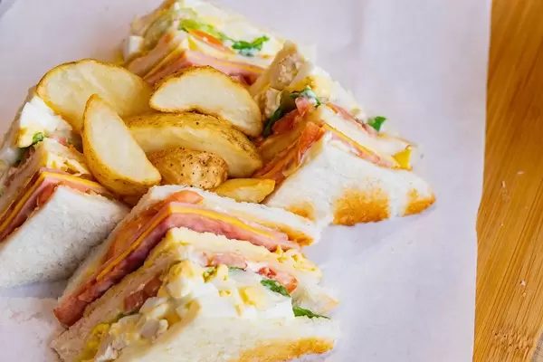 Close up of clubhouse sandwich with potato wedges