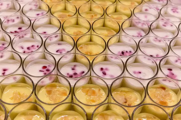 Close-up of dessert, pomegranate-oranges Lassi and saffron yoghurt with grapes, cardamom, blueberries, honey and almond flakes at Barcamp OMWest19