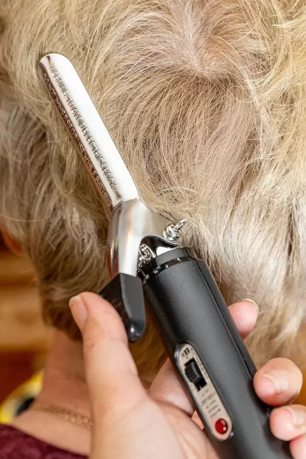 Close-up of electric curling iron on woman's hair