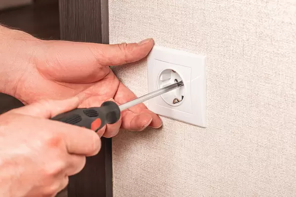Close-up of electrician hands with screwdriver installing wall socket