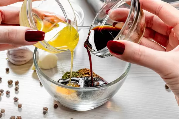 Close up of female hands pouring honey and soy sauce into a bowl with spices