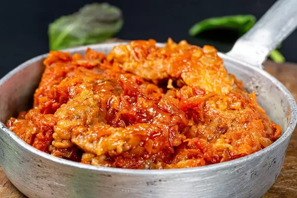 Close- up of fish with tomato sauce in a frying pan