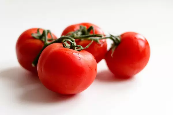 Close-up of four red tomatoes, fresh and washed, on a white background