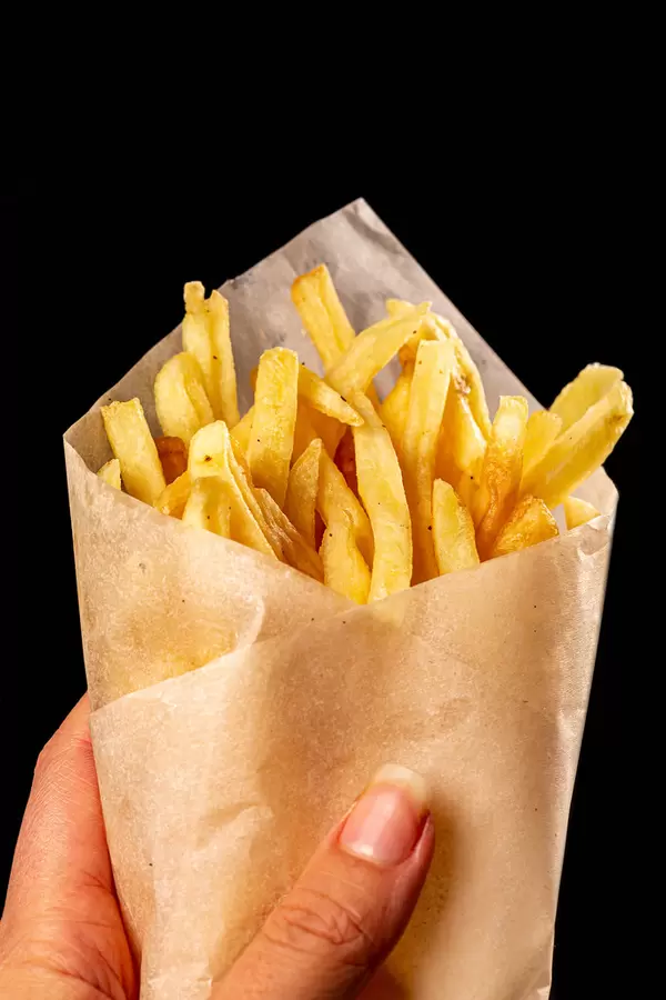 Close-up of french fries in a female hand on a black background
