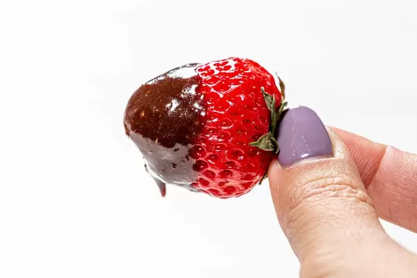 Close-up of fresh strawberries in milk chocolate in a woman's hand (Flip 2019)