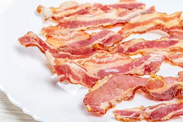 Close-up of fried bacon slices on a white plate