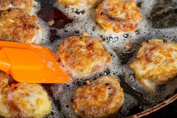 Close up of fried bagels with meat filling in a frying pan