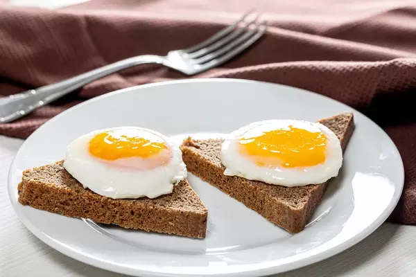 Close-up of fried eggs on pieces of black bread (Flip 2019)
