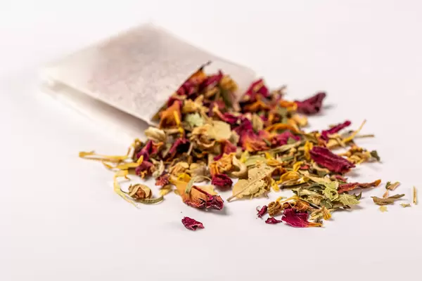 Close-up of green tea sprinkled with flowers petals and tea bag