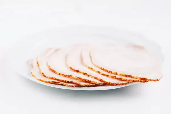 Close up of ham slices n white plate. White background.