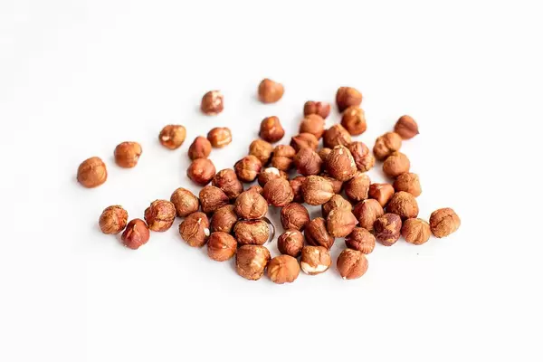Close up of heap of raw hazelnuts on white background